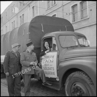 Discussion entre un sergent, un commandant et une volontaire de la Fondation du maréchal de Lattre à bord d'un camion cinéma.