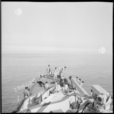 Sur le pavois de l'escorteur Hova, des matelots de l'équipage lèvent l'ancre au cours d'une manoeuvre de mouillage.