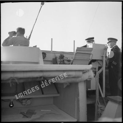 Un élément de l'équipage, un enseigne de vaisseau de 1re classe et un capitaine de frégate en mission de surveillance sur la passerelle de l'escorteur Hova.