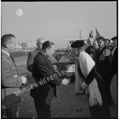 Poignée de main entre le ministre résident Robert Lacoste et la veuve du colonel Colonna d'Ornano lors de la cérémonie organisée pour le transfert du cercueil du colonel à Alger.