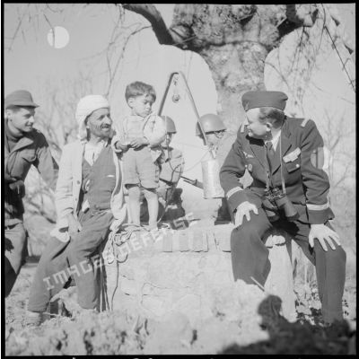 Discussion entre un capitaine de l'armée de l'Air et un Algérien assis sur un puits à Blida.