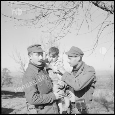 Deux soldats portent un jeune enfant algérien dans leurs bras à Blida.