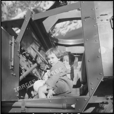 Une petite fille et un jeune enfant algériens posent à bord d'un véhicule militaire.