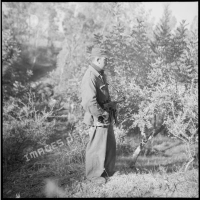 Un soldat patrouille avec son pistolet-mitrailleur dans un jardin de Blida.