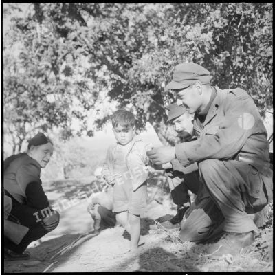 Deux soldats jouent avec un enfant algérien à Blida.