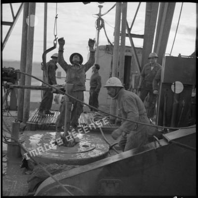 Des ouvriers de la Compagnie française des pétroles en Algérie oeuvrentt sur la table de rotation de la plateforme de forage pétrolier d'Hassi Messaoud.