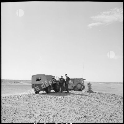Conversation entre trois hommes près de leurs véhicules sur le site pétrolier d'Hassi Messaoud.
