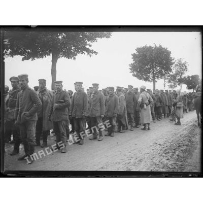 Des prisonniers allemands capturés lors de l'offensive de Champagne attendent sur la route de Souain. [légende d'origine]