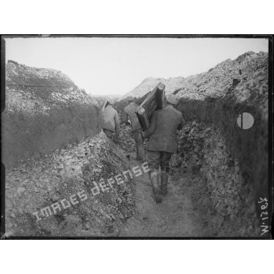 Un soldat transporte des passerelles utilisées pour franchir les tranchées en cas d'attaque. [légende d'origine]