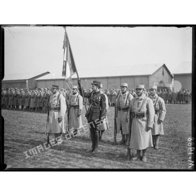 Le Sous-lieutenant Guynemer porte drapeau au milieu des troupes lors de la cérémonie sur le terrain d'aviation de Longvic-Dijon. [légende d'origine]