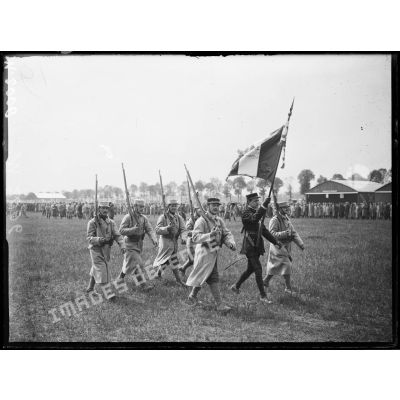 Le Sous-lieutenant Guynemer porte drapeau au milieu des troupes lors de la cérémonie sur le terrain d'aviation de Longvic-Dijon. [légende d'origine]