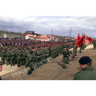 Les militaires de l'armée de libération du Kosovo (UCK) en rangs avec des drapeaux à l'emblème de l'armée de libération du Kosovo (UCK).