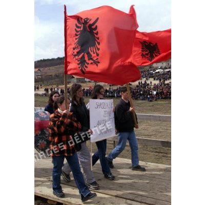 Des Kosovars défilent avec une banderole en hommage à la famille Jashari et des drapeaux de l'armée de libération du Kosovo (UCK).