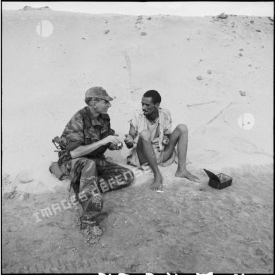 Le 2e classe Michel Nicod du 2e RPC (régiment de parachutistes coloniaux) offre du feu à un Egyptien, au cours d'une reconnaissance armée en jeep à l'est de Port-Fouad, le long de la côte.