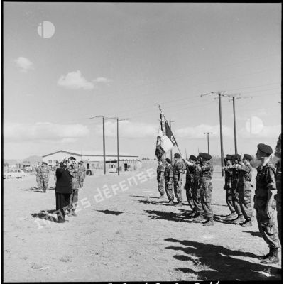 Le vice-amiral d'escadre Barjot salue le drapeau d'une unité parachutiste lors d'une cérémonie du 11 novembre au camp X (Chypre).