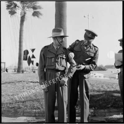 Le général britannique Sir Hugh Stockwell ajuste le brassard "United Nations" d'un observateur australien de l'ONU à Port-Saïd.