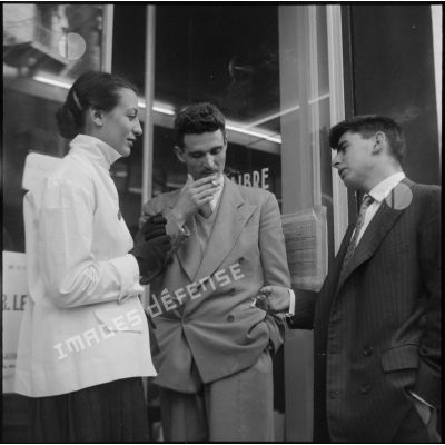 Trois personnes devant une salle d'exposition.