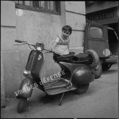 Une fillette juchée sur la selle d'un scooter,Alger.