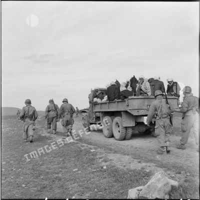 Région d'El Gor. Des hommes sont transportés en camion vers le poste, accompagnés par des militaires.