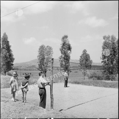 Deux soldats et deux enfants devant un filet de volley-ball.
