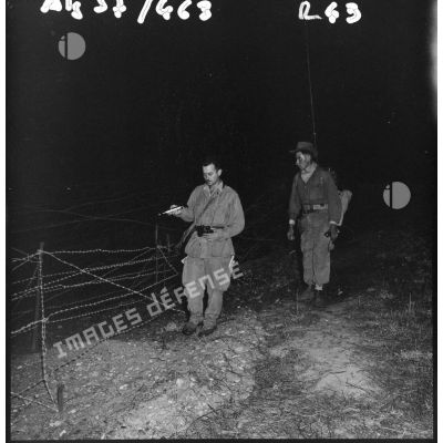 Patrouille de nuit dans le réseau électrifié. Le sous-lieutenant Coppola de la 9ème compagnie du 3/60ème régiment d'infanterie (RI) vérifie les fils barbelés.