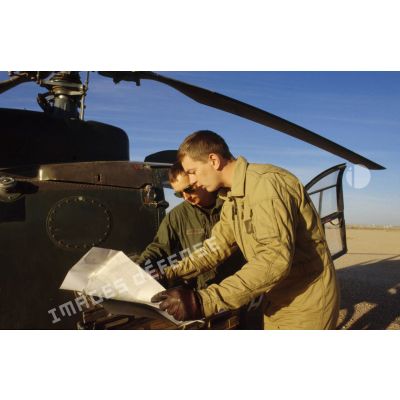 Deux pilotes de l'ALAT (aviation légère de l'armée de terre) étudient la carte avant leur départ en mission à bord d'un hélicoptère de combat Gazelle.