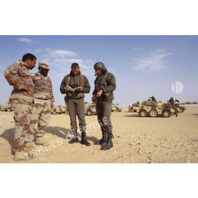 Deux soldats demandent leur route dans le désert à des militaires saoudiens, à l'aide d'un dictionnaire, pour la colonne de blindés de reconnaissance ERC-90 Sagaie du 1er RHP (régiment de hussards parachutistes).