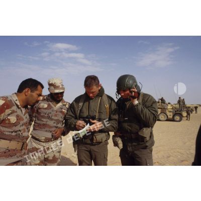 Deux soldats demandent leur route dans le désert à des militaires saoudiens, à l'aide d'un dictionnaire, pour la colonne de blindés de reconnaissance ERC-90 Sagaie du 1er RHP (régiment de hussards parachutistes).