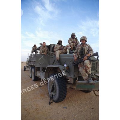 Photographie de groupe de soldats de la 82e Airborne juchés sur l'avant d'un camion M939 tractant un obusier M198 de 155 mm dans un poste américain dans la ZDO (zone de déploiement opérationnel) Olive