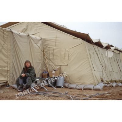 Un personnel féminin fume à l'entrée d'une tente du campement militaire de la base air américaine de CRK (camp du roi Khaled).