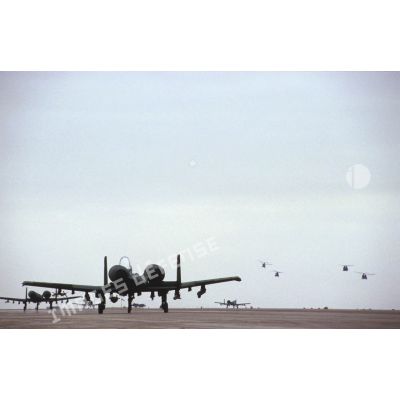 Avions d'appui rapproché Fairchild A-10 Thunderbolt-II garés sur la piste de la base air américaine de CRK (camp du roi Khaled), survolée par des hélicoptères.