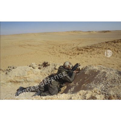 Soldat en position de tireur couché au FAMAS dans un trou de combat lors d'un exercice de tir du 11e RAMa (régiment d'artillerie de marine) en ZDO (zone de déploiement opérationnel) Olive.