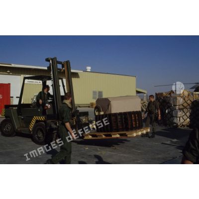 Un transpalette décharge des caisses de matériel près d'un hangar de la base aérienne du CRK (camp du roi Khaled).