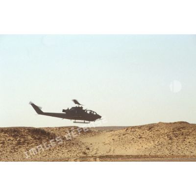 Aux alentours du CRK (camp du roi Khaled), un hélicoptère de lutte antichar Bell 209 Huey-Cobra en vol.