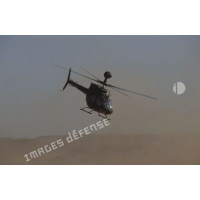 Aux alentours du CRK (camp du roi Khaled), un hélicoptère de reconnaissance et d'observation Bell-OH58 Kiowa muni d'un système de visée installé au-dessus du rotor en vol.