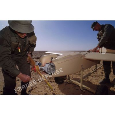 Mise en oeuvre du système de drones MART Mk II en ZDO (zone de déploiement opérationnel) Olive par deux soldats qui s'affairent autour de l'ALT (avion léger télécommandé) à voilure fixe.