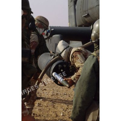 En ZDO (zone de déploiement opérationnel) Olive, un soldat introduit une roquette de 70 mm dans le panier de roquettes d'un hélicoptère de combat américain Hughes-AH 64 Apache de retour de mission.