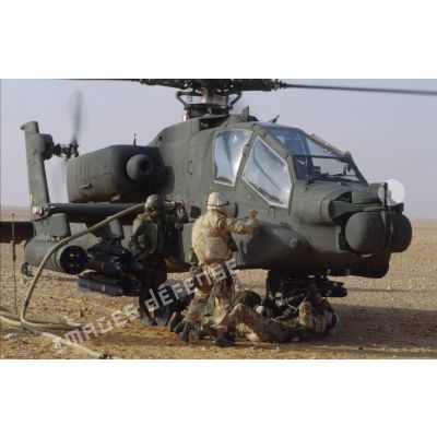 En ZDO (zone de déploiement opérationnel) Olive, des soldats ravitaillent en carburant un hélicoptère de combat américain Hughes-AH 64 Apache rotors tournant dans le désert.