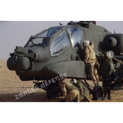 En ZDO (zone de déploiement opérationnel) Olive, des soldats ravitaillent en carburant un hélicoptère de combat américain Hughes-AH 64 Apache dans le désert.