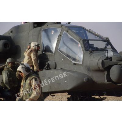 En ZDO (zone de déploiement opérationnel) Olive, un soldat discute avec le copilote-tireur d'un hélicoptère de combat américain Hughes-AH 64 Apache par la verrière latérale du cockpit.