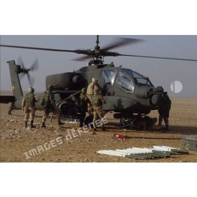 En ZDO (zone de déploiement opérationnel) Olive, des soldats ravitaillent en carburant un hélicoptère de combat américain Hughes-AH 64 Apache rotors tournant dans le désert.