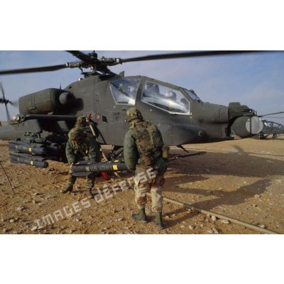 En ZDO (zone de déploiement opérationnel) Olive, des soldats approvisionnent en missiles Hellfire un hélicoptère de combat américain Hughes-AH 64 Apache de retour de mission rotors tournant.