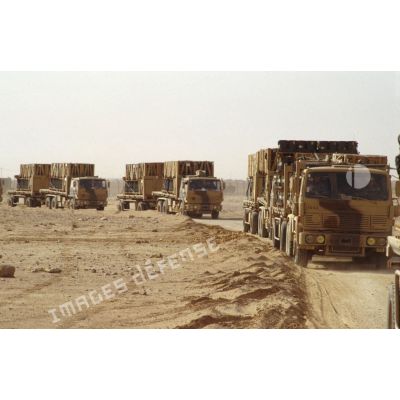 Convoi de VTL (véhicule de transport logistique) chargés et tractant leur remorque en progression sur une piste dans le désert.