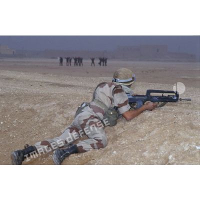 Aux abords d'Al Salman, tandis que des soldats irakiens mains en l'air se rendent, un soldat du 3e RIMa (régiment d'infanterie de marine) est posté en position de tireur couché, armé d'un FAMAS.