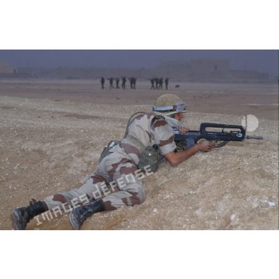 Un soldat irakien, blessé lors de l'attaque, est couché au sol, sur le dos, surveillé par des soldats français.