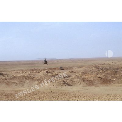 Survol par un hélicoptère Gazelle d'une position fortifiée irakienne et d'un char de combat T-55 détruits dans la zone de Rochambeau.