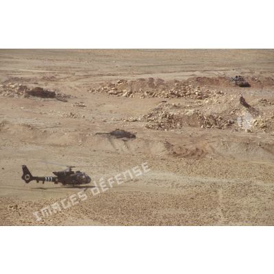 Un hélicoptère de combat Gazelle posé dans la zone de Rochambeau sur une position irakienne à proximité de chars de combat T-55 et d'un transport de troupes chenillé MT-LB irakiens détruits.