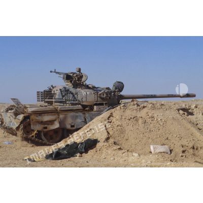 Un char de combat T-55 irakien, armé d'un canon antichar D-10T2S de 100 mm et d'une mitrailleuse lourde DShKMT de 12,7 mm, protégé par un merlon de sable vers l'avant.