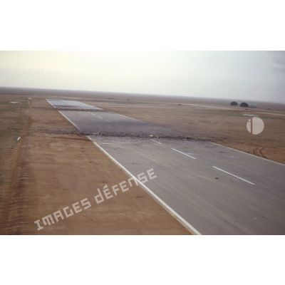 Vue aérienne de la piste détruite de la base aérienne d'Al Salman avec des impacts d'explosions.