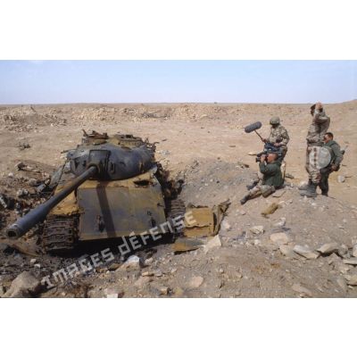 Une équipe de tournage de l'ECPA (Etablissement cinématographique et photographique des Armées) a pour sujet un char de combat T-55 irakien détruit.